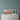 A styled bedroom scene featuring a white three-drawer dresser against a bold green and white checkerboard patterned wall. 
